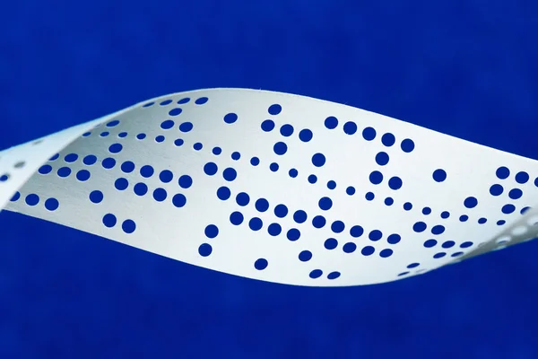 Closeup of perforated punched tape on blue background