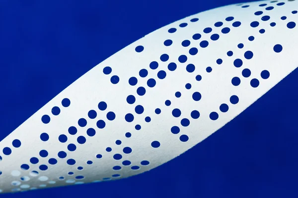Closeup of perforated punched tape on blue background