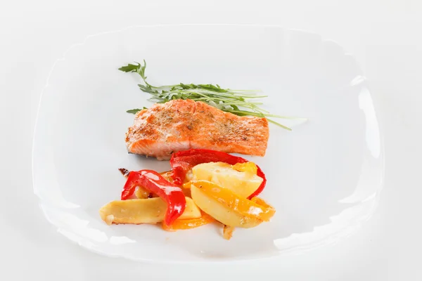 Grilled salmon fillet with vegetables, spices and arugula on a plate