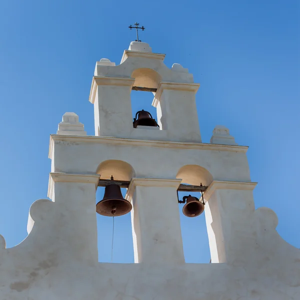 Close up of the Mission Church Bells - an old mission church bell tower wooden door against a white washed plaster wall