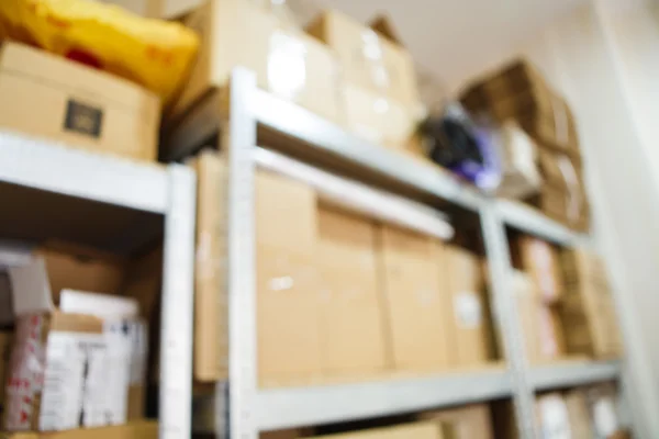 Blurred image of storage racks with carton boxes in warehouse for small business