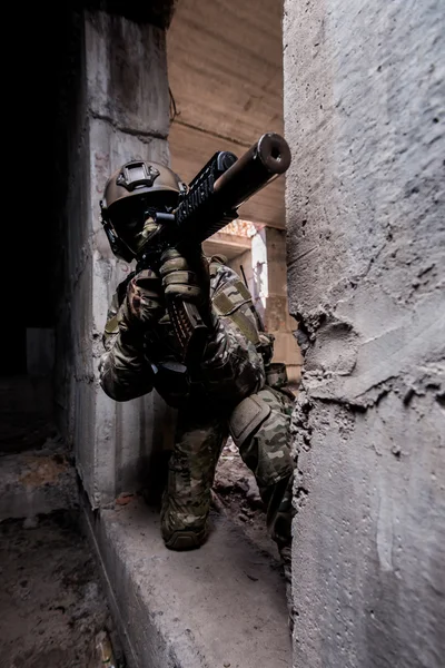 Russian army soldier shoots a machine gun out of hiding in an abandoned building