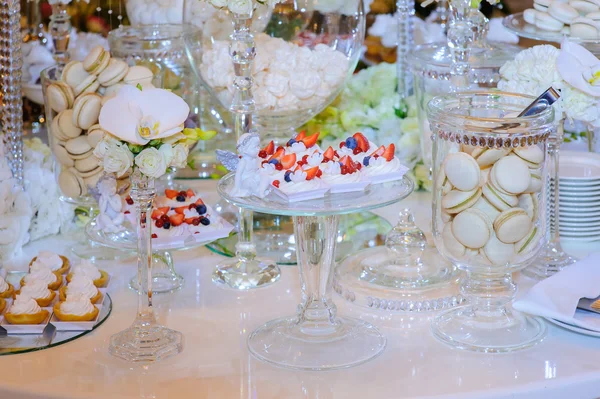 Macaroon, cake,meringue and flowers on dessert table.