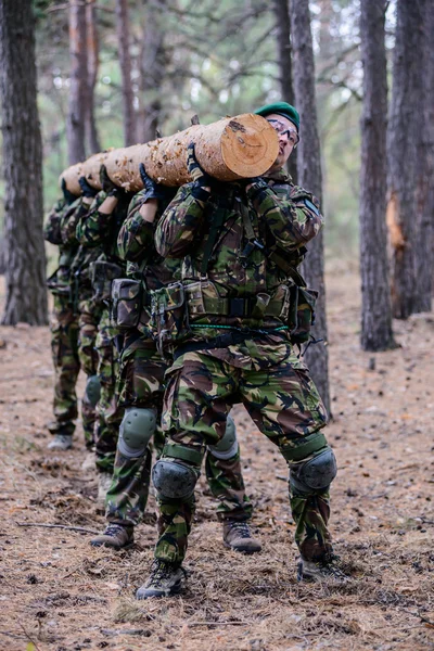 Group of soldiers in the forest holding a big log