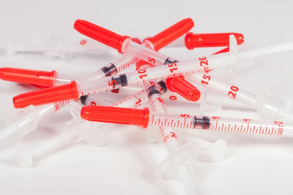 Pile of Empty Syringes with Red Safety Caps