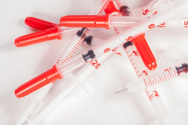 Pile of Empty Syringes with Red Safety Caps