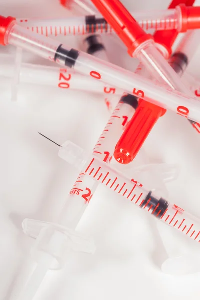 Pile of Empty Syringes with Red Safety Caps