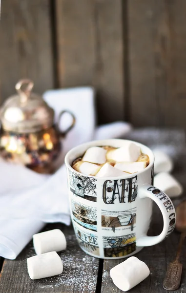 White marshmallow in the cup of coffee on the old wooden background