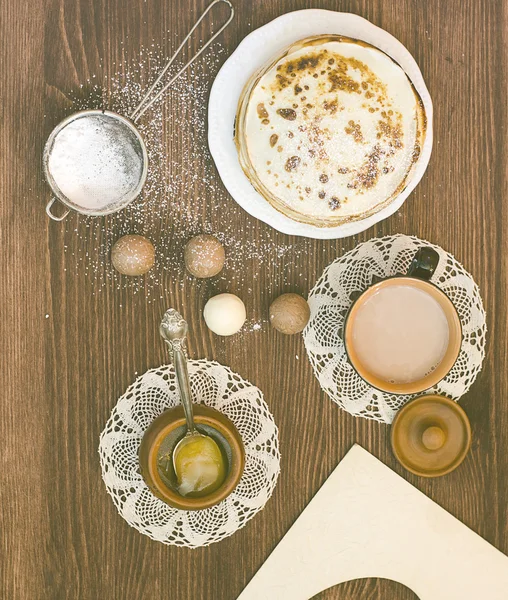 Pancakes with sugar powder and honey and cup of coffee on the vintage napkin on the brown wooden background, breakfast, Chocolate sweets. Frame for photos.  Toned pictured, selective focus