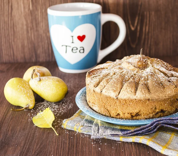 Pear pie with pears and big cup of tea on the wooden background