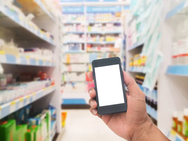 Hand with smartphone on blurred pharmacy store