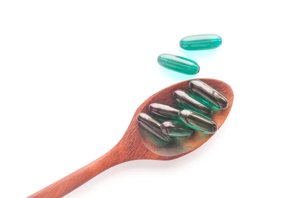 Pills capsule on wooden spoon isolated