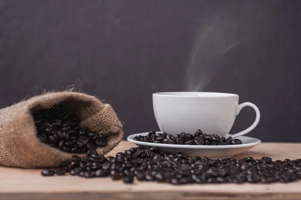 Cup of coffee with roasted coffee on a wooden and smoke