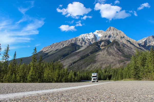 White truck driving through canadian rocky mountains during summ