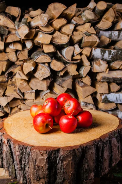 A few apples on the stump in the background of birch firewood