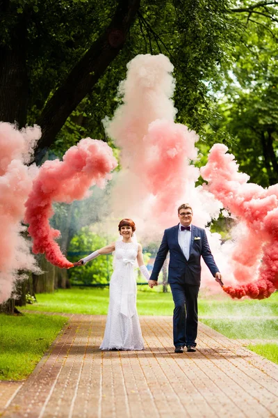 The bride and bridegroom with a red smoke on background summer nature