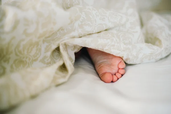 The baby\'s legs visible from under the blanket