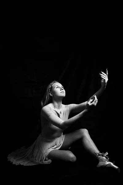 Black and white photography portrait of beautiful young woman in dancing sitting on dark  background copy space