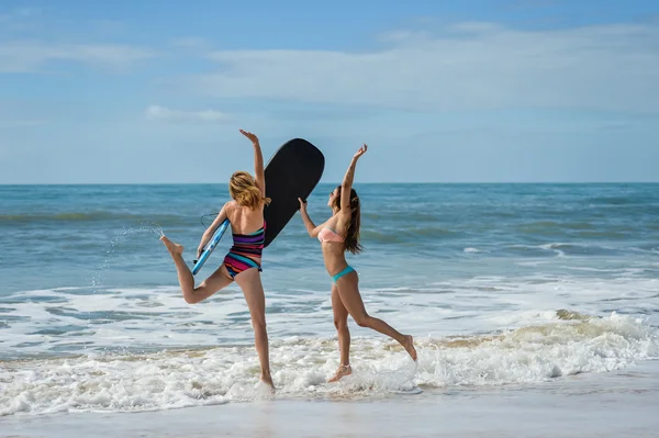 Healthy athletic surfer girl friends with fit bodies holding bodyboards