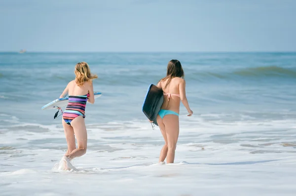 Healthy athletic surfer girl friends with fit bodies holding boards