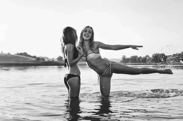 Black white photography of 2 young beautiful best girls friends in bikini having fun relaxing in water on summer day