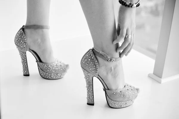 Black white photography of legs in high heel shoes on light background closeup