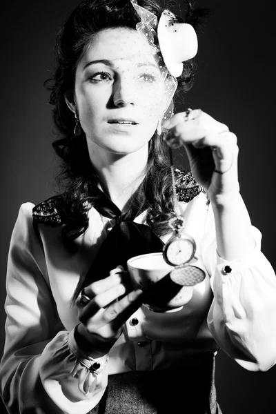 Portrait of beautiful young lady with cup of drink and pocket watch on light background