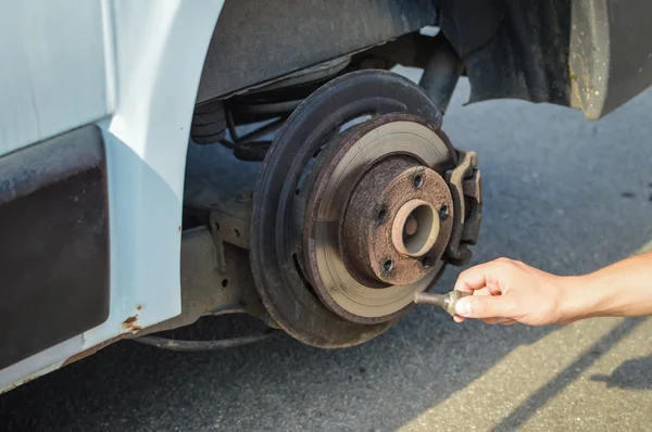 Closeup of person changing vehicle tire with bare hands. Outdoors background