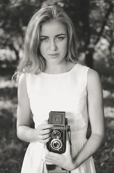 Black white photography of young beautiful blond woman with retro camera in summer nature background