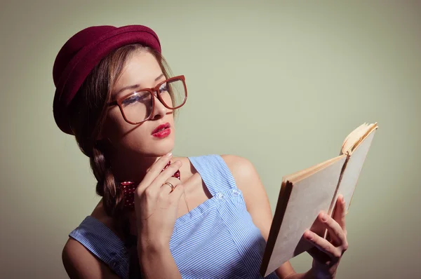 Girl in a red hat and glasses reading a book