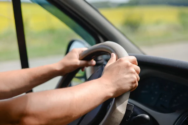 Mans hands gripping wheel of car