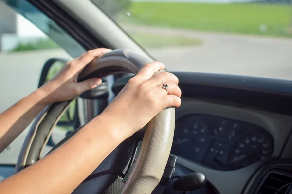 Young womans hands holding steering wheel inside car in summer