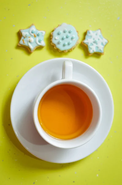 Picture of three ginger cookies and cup of tea over light table