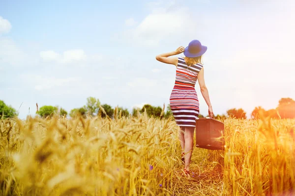 Girl in blue hat walking away in golden sunlight countryside