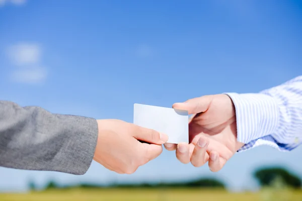 Womans hand giving blank white business card to mans hand