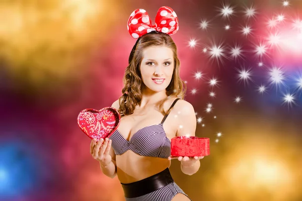 Portrait of sexy beautiful young lady in striped underwear showing red heart shaped giftbox