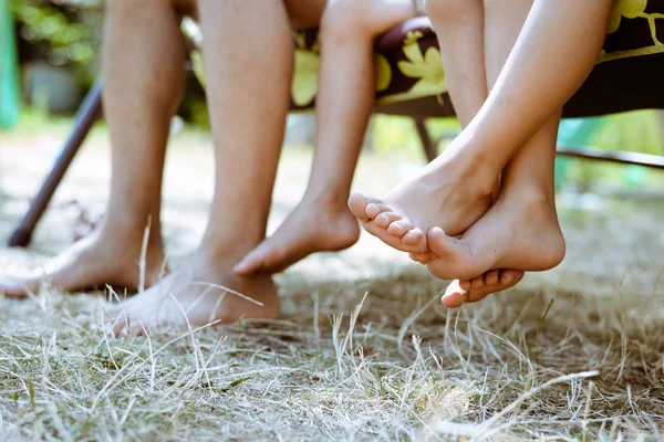 Closeup of man and children legs barefoot on garden swing