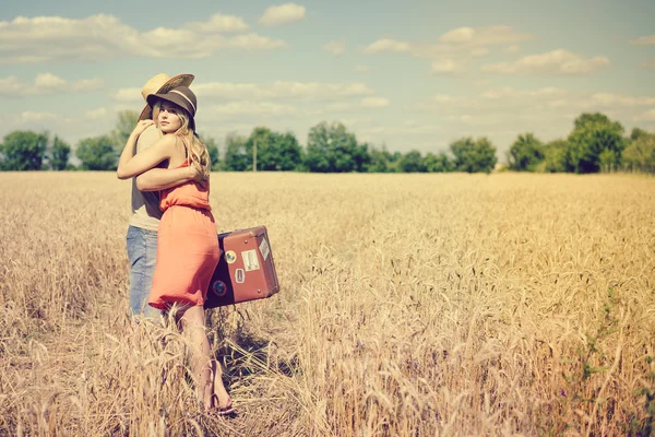 Romantic young couple with old suitcase hugging in summer countryside