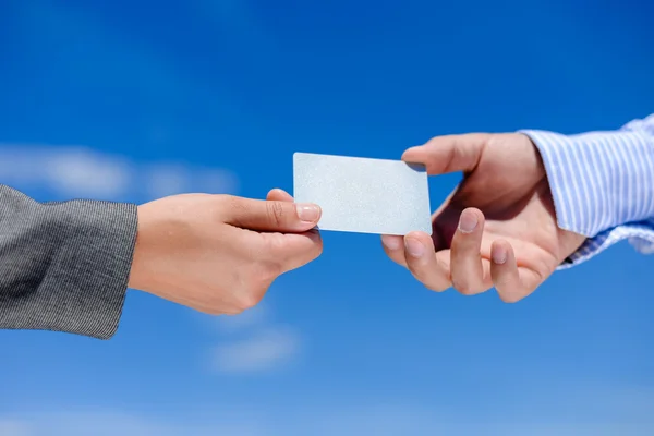 Young womans hand giving blank business card to mans hand