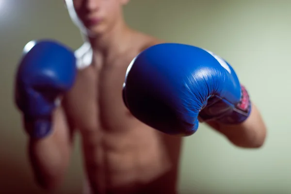 Male training box punches with bandages closeup on strong muscles of torso over dark background. Boxing workout.