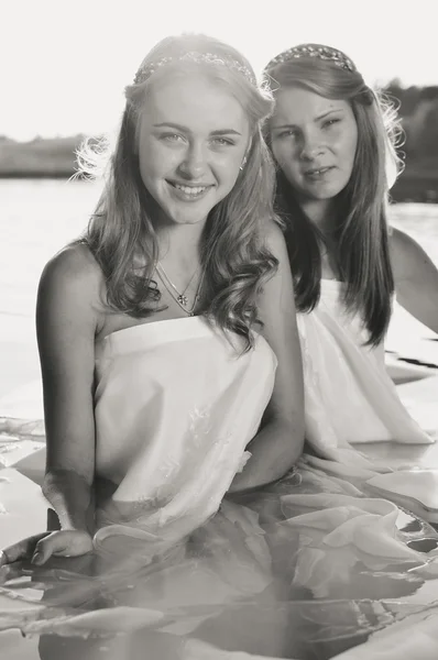 2 beautiful princess young ladies in white dresses on summer water outdoors background, black and white picture