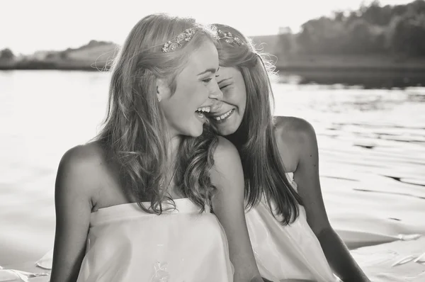 Black and white photography of 2 beautiful princess young ladies in white dresses on summer water outdoors background