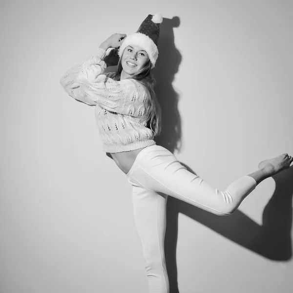 Picture of happy dancing girl with Christmas hat and present box. Black and white photography