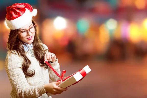 Picture of pretty girl in Santa red hat and glasses opening gift box