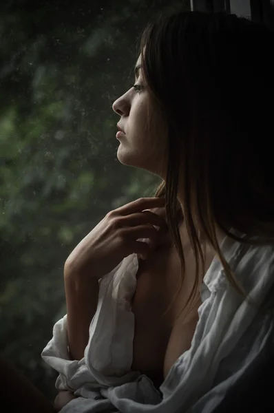 Young beautiful woman silhouette looking out the window, portrait