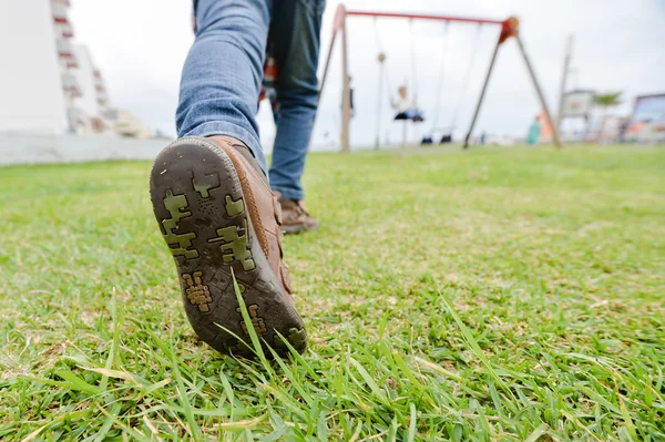 Closeup of child leg and boot sole on grass playground