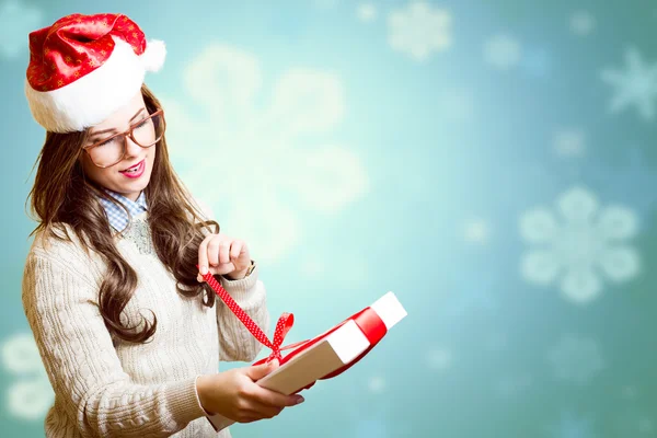 Pretty girl in Santa red hat and glasses opening gift box