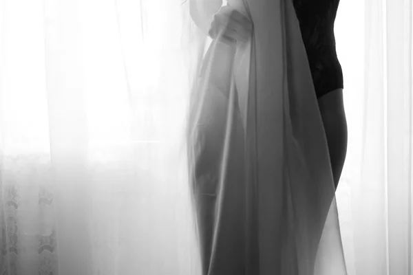 Female silhouette hiding behind tulle curtain. Black and white photography