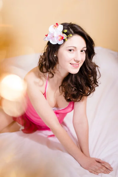 Beautiful young woman wearing nightgown with white orchid in hair