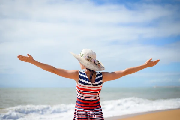 Excited lady in hat spreading hands with joy facing sun